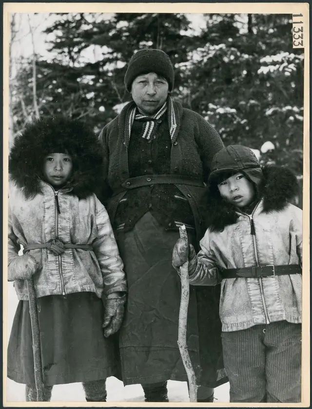 A woman and two children in fur-trimmed parkas